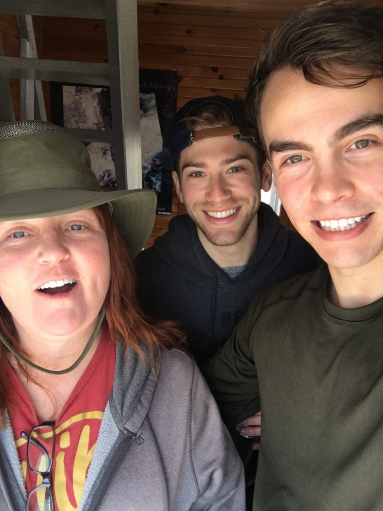 Three people stand together and smile at the camera in a selfie.