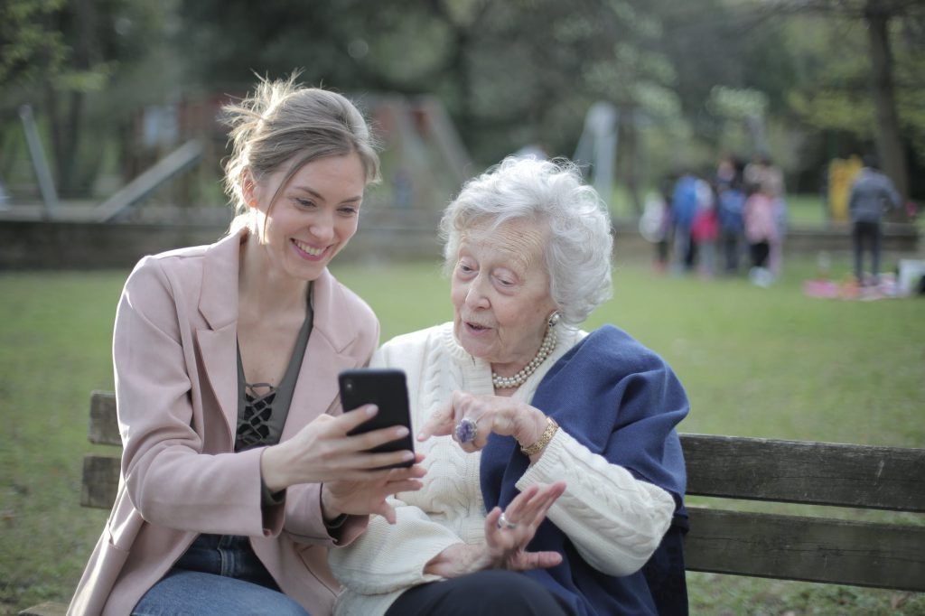 A young female sitting with an older woman on a park bench
