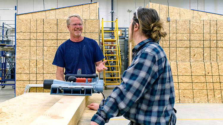 Smiling-carpentry-technician-Alan-VanClieaf-works-with-a-student-in-the-shop-space