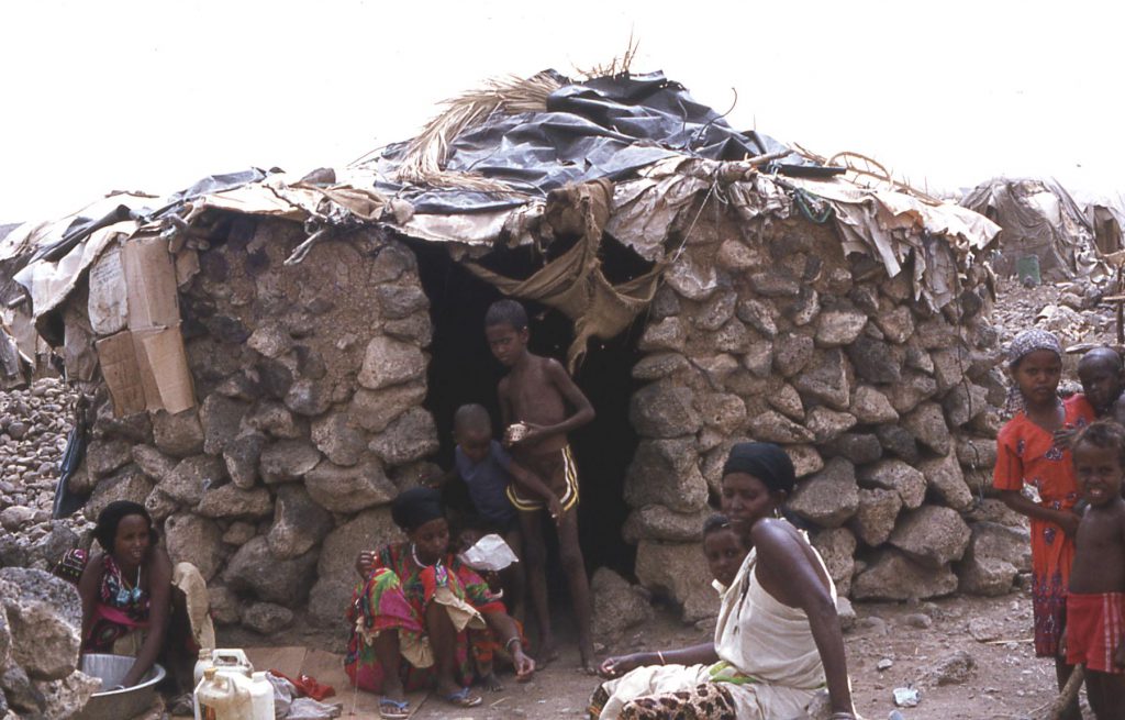 People hang out in front of a hut in an African village.