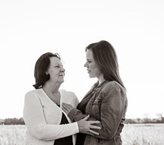 Two women standing side-by-side in a field.