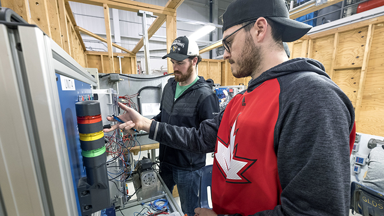 Two-male-Electrical-Techniques-students-work-on-an-electrical-board-in-Skilled-Trades-Centre