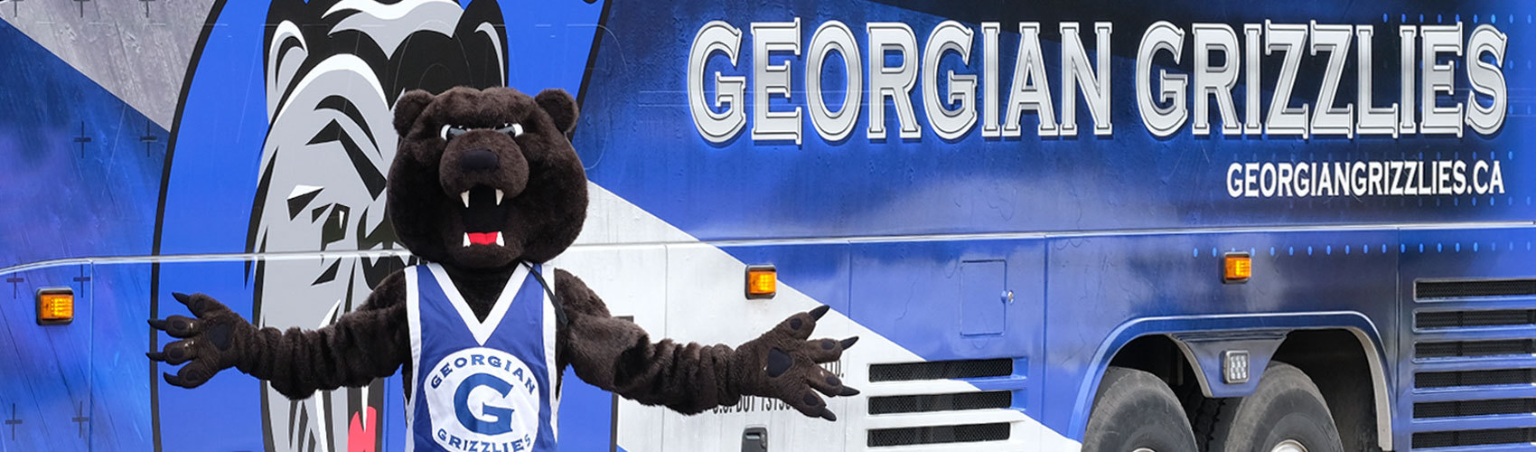Georgian Grizzly standing beside Georgian Grizzly wrapped bus