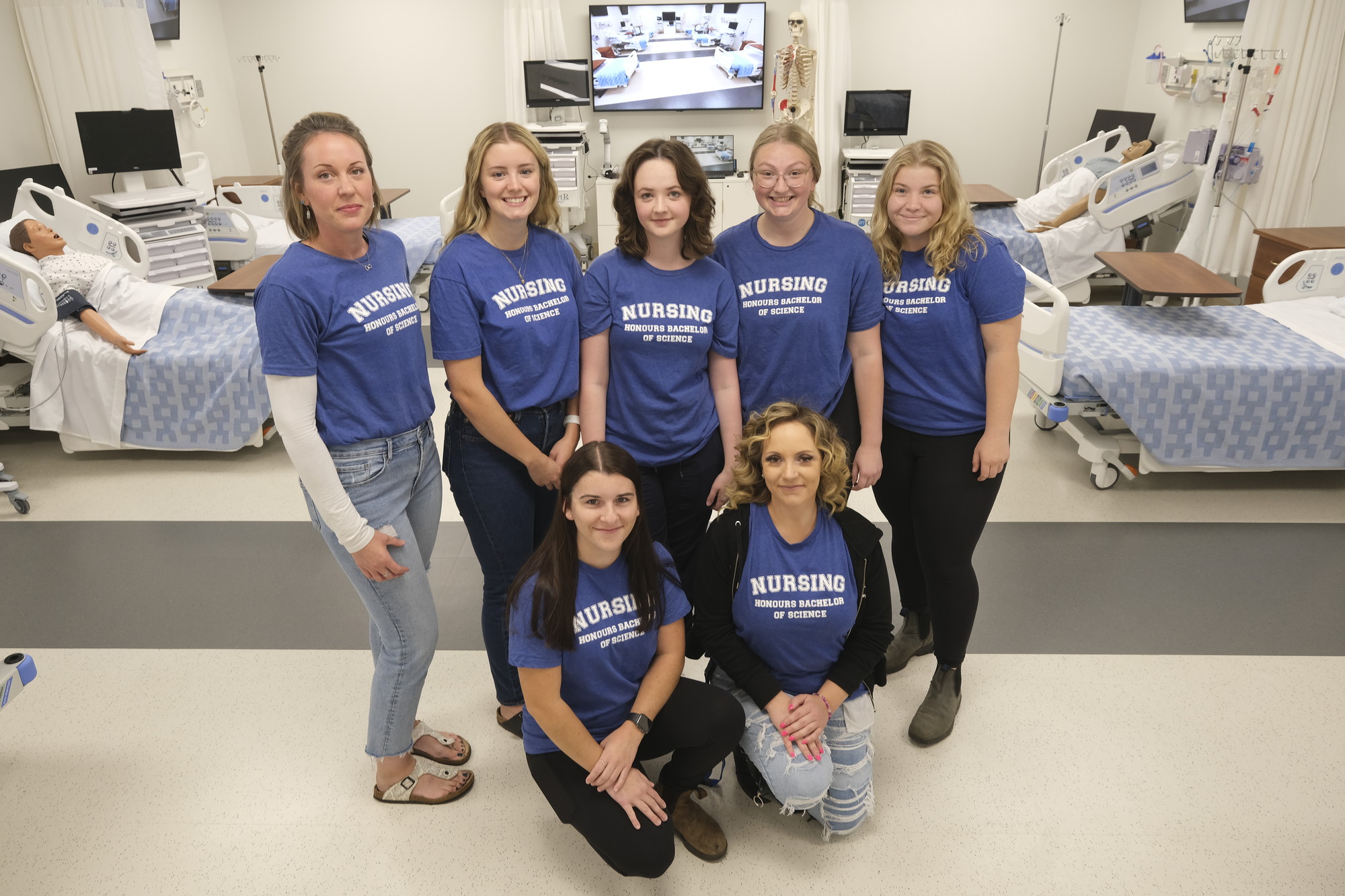 Sven young females wearing blue t-shirts and jeans standing in a hospital room