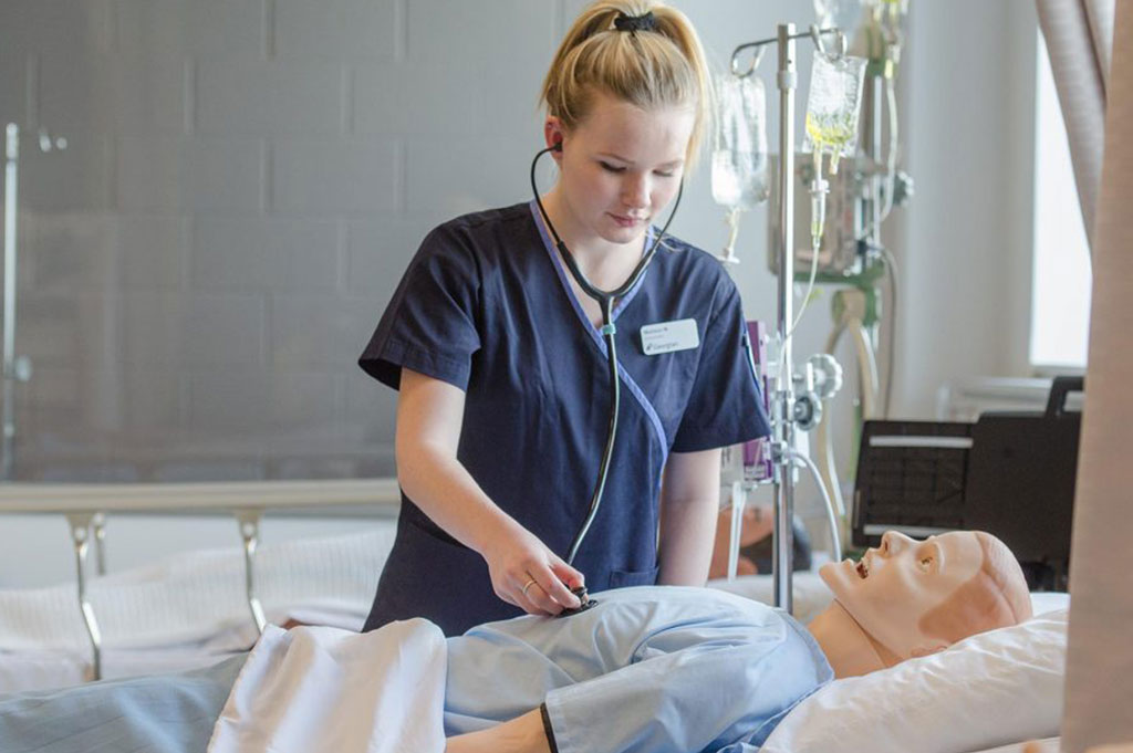 female BSCN nursing student performing a stethoscope auscultation on a patient simulator in Georgian College's nursing lab