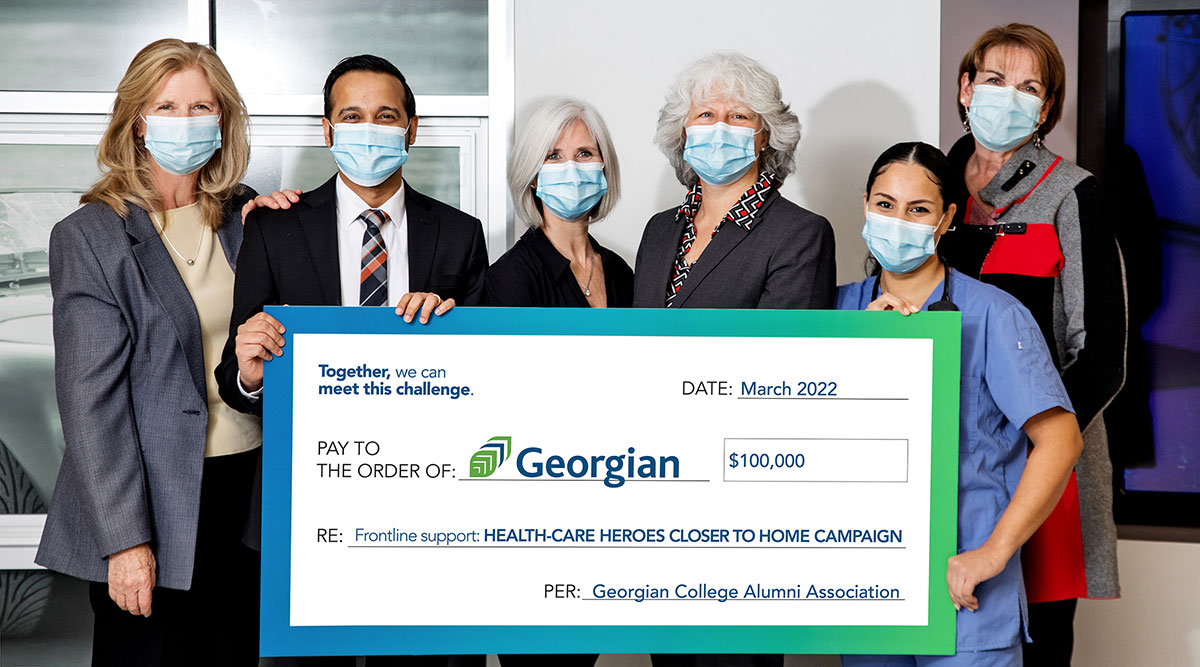 Six people dressed in business attire and wearing face masks holding up a big cheque to Georgian College for $100,000