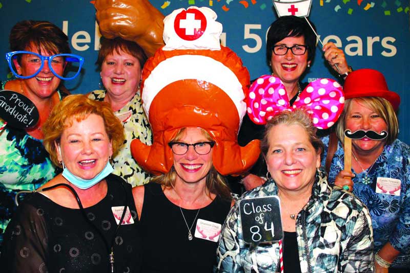 A group of Georgian College nursing alumni with accessories and props at a reunion
