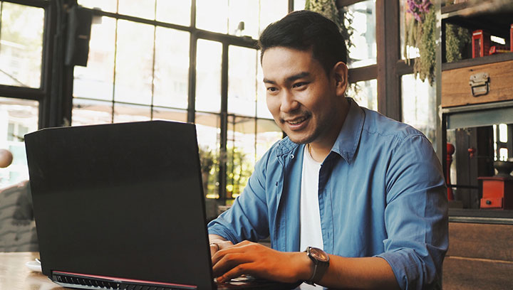 Person smiling while sitting at a desk using a laptop computer