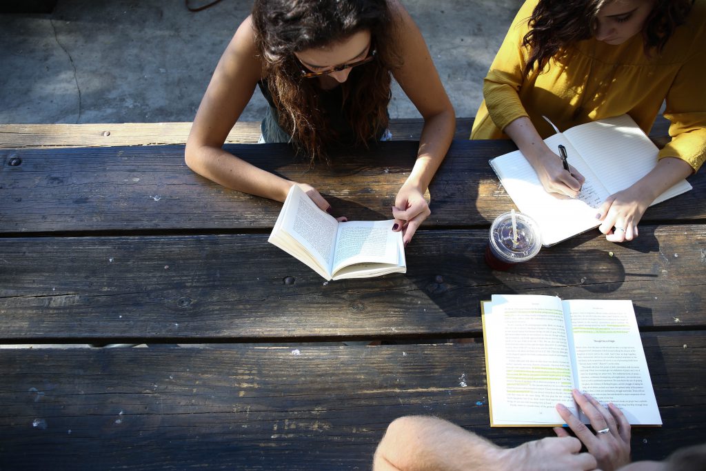 3 female students sitting at a picnic table working on homework