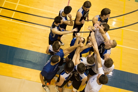 A volleyball team stands in a huddle