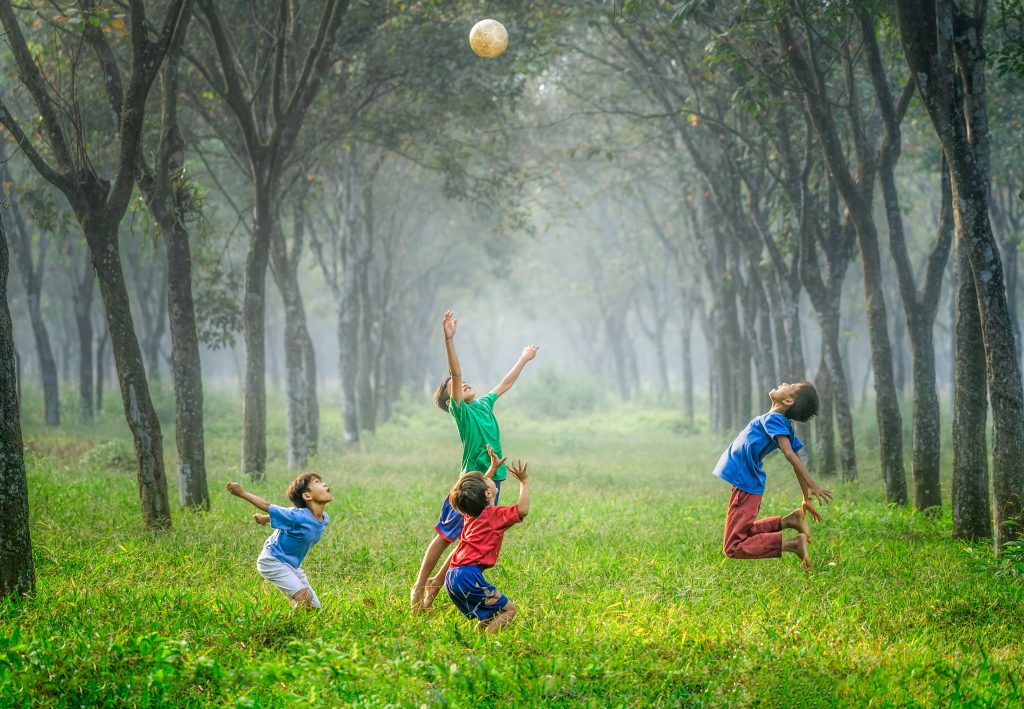 Children playing with a ball in a forest.