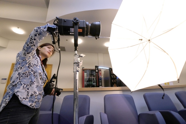 A photography student adjusting camera lighting to capture a photograph