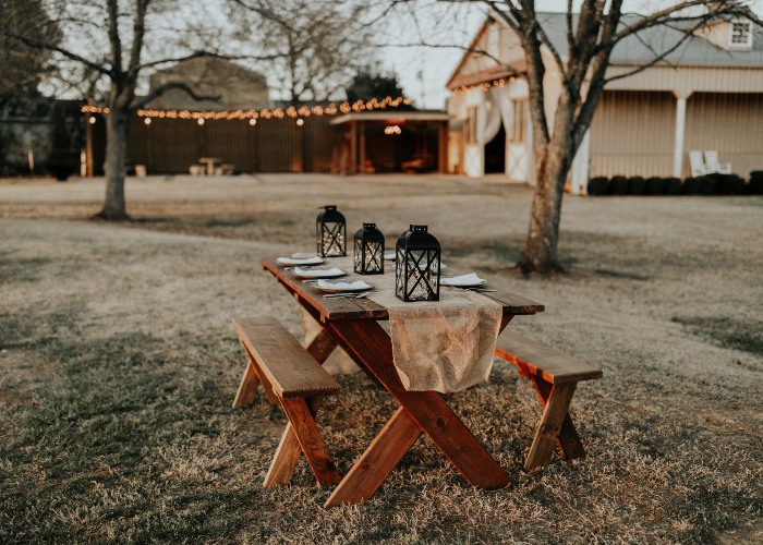 A picnic table with lanterns and place settings