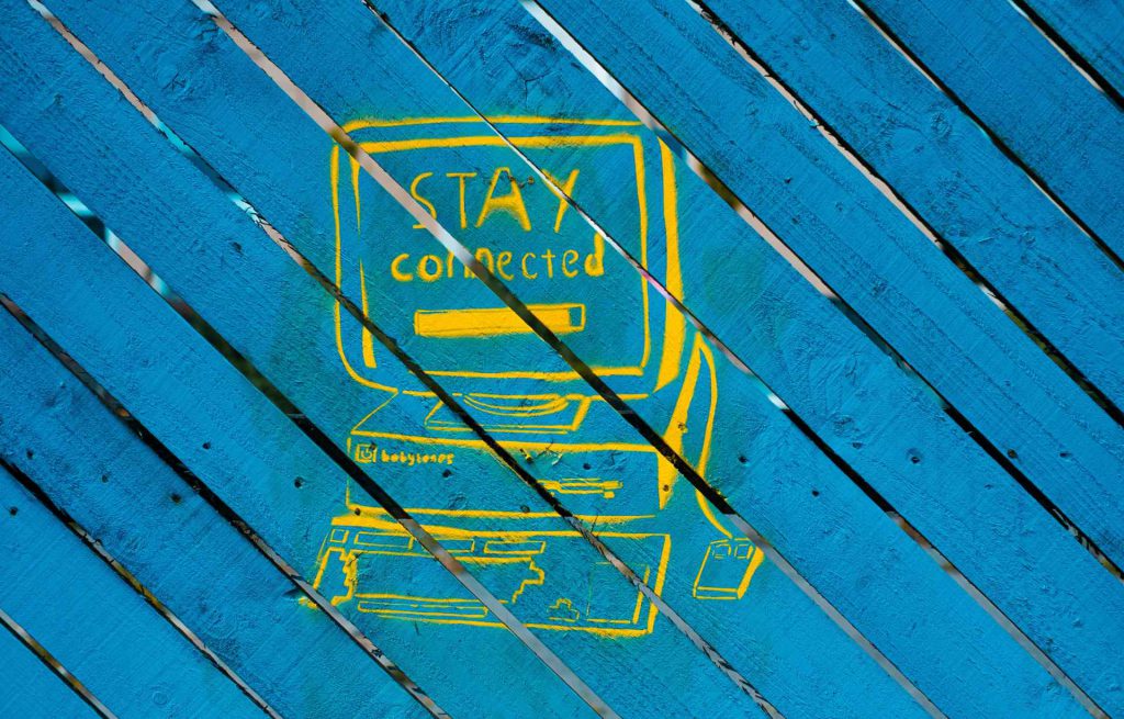 yellow graffiti of a computer that reads "stay connected"