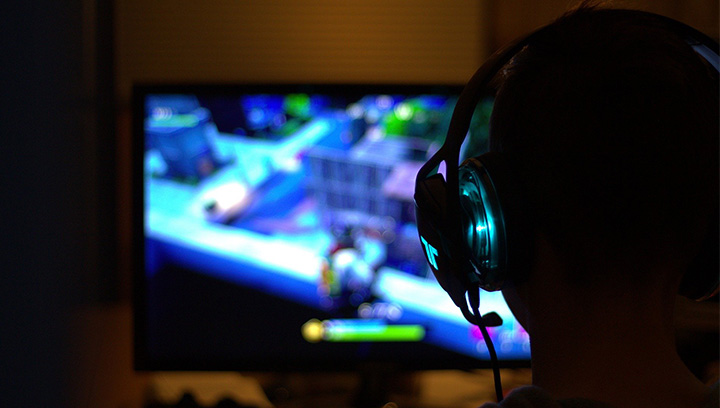 Person in a dark room wearing a headset and playing video games