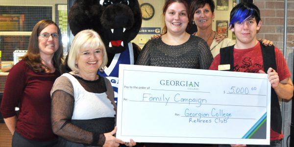 A group of people and Growler, Georgian's bear mascot, holding a supersized $5000 cheque