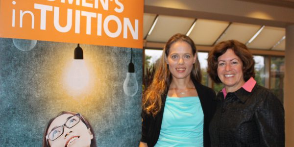 Shivonne OBrien and Giselle Bodkin standing next to a WOMEN's inTUITION poster