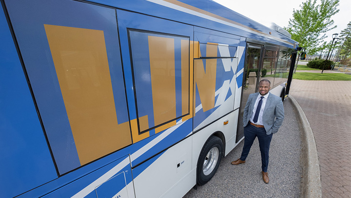 Ronjay Clarke standing next to a Simcoe County LINX bus outside the Georgian College Barrie Campus