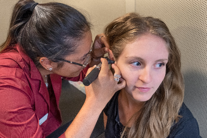 Communicative Disorders Assistant using an otoscope while looking into the ear of another student