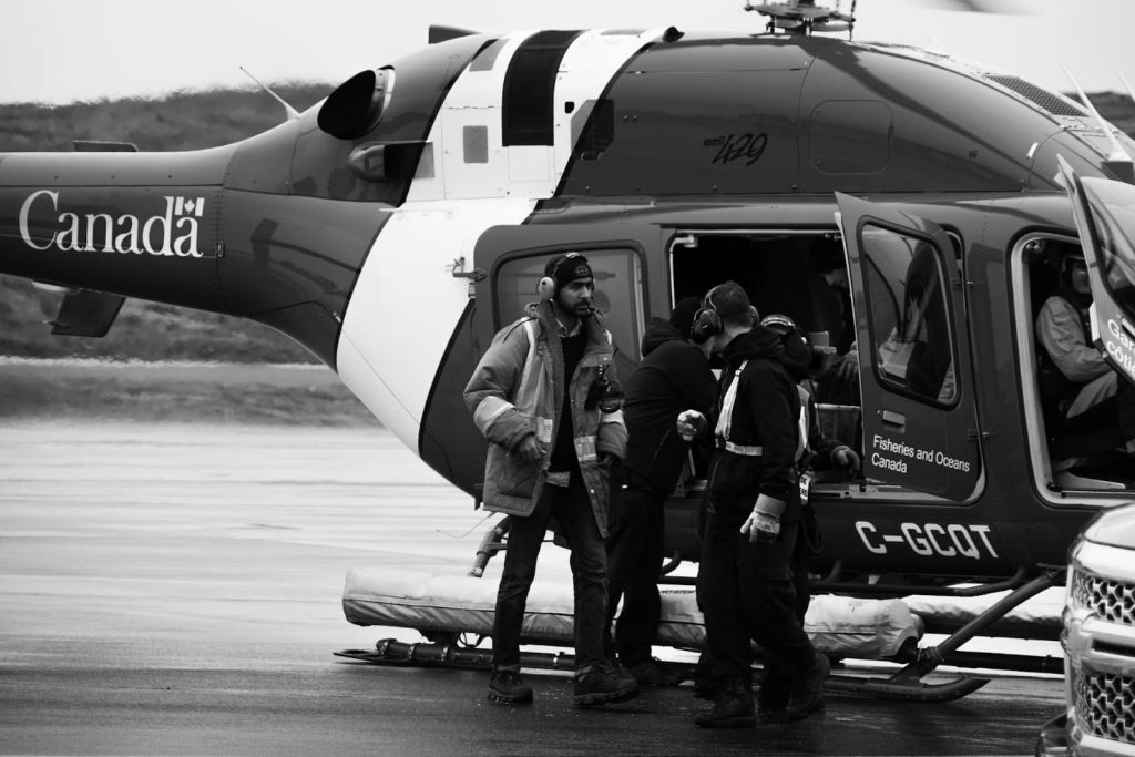 Black and white photo of 3 workers opening the doors to a Canadian government helicopter.