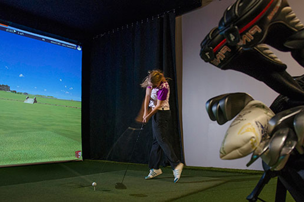 a female student practising in Georgian's instructional golf lab