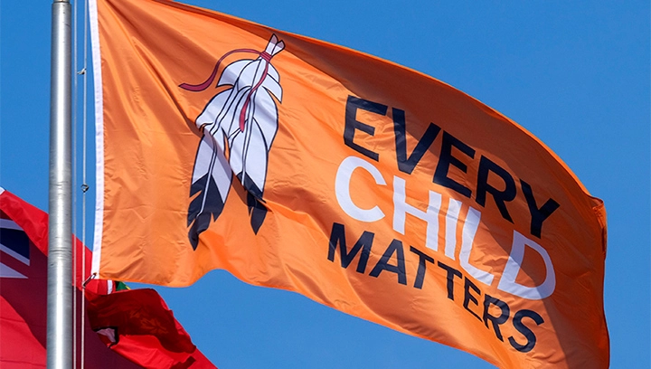 An "Every Child Matters" orange flag flying at a flagpole in front of one of our campuses.