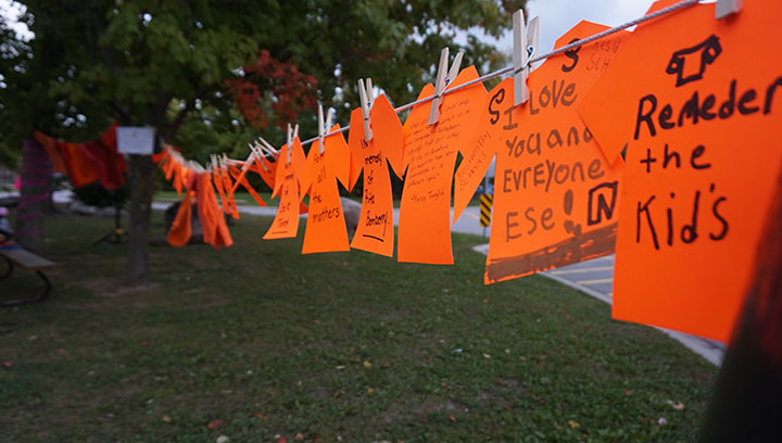 Several orange shirts hung on a clothes line between two trees