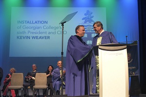 President and CEO shakes Board Chair's hand on stage during installation ceremony