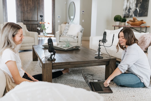 image of two women recording a podcast with microphones and a laptop