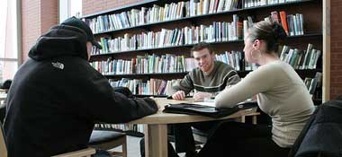 Three students working together at a table in the library