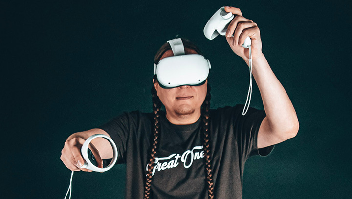 A person wearing a virtual reality head set and holding hand controls