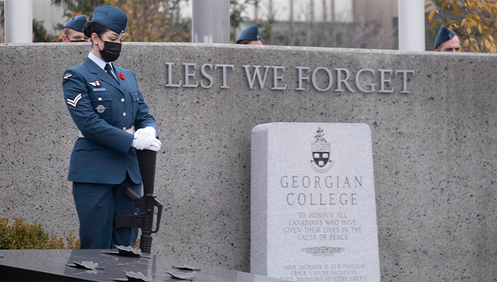 Member of Honour Guard in blue military uniform stands at Georgian College Barrie Campus Cenotaph on Remembrance Day 2021