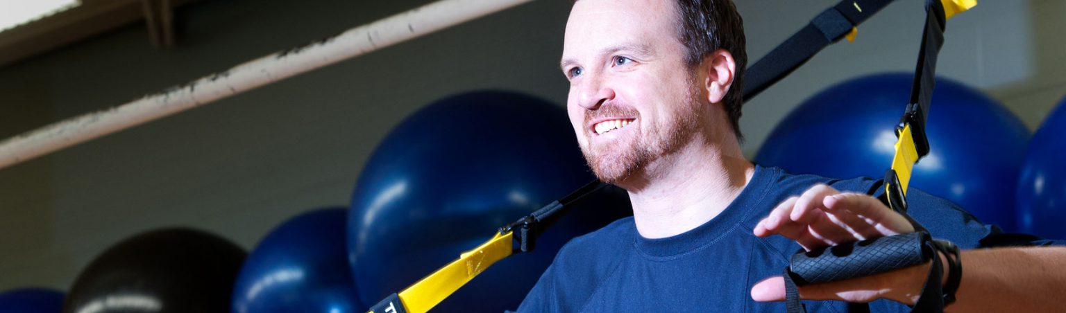 Person in an navy blue athletic t-shirt using resistance bands for strength training in a fitness centre setting