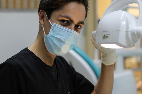 dental hygienist student with mask on holding on to light