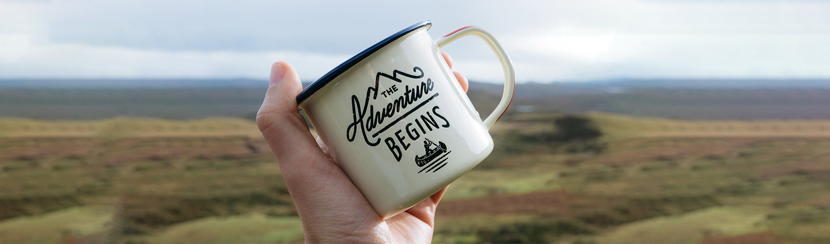 Orientation banner - photo of a mug that says "The Adventure Begins"