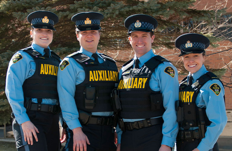 Four auxiliary officers standing side-by-side posing with smiles