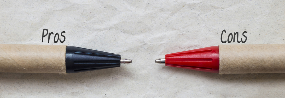 two pens, one black, one red, with the word "pros" and "cons" written above them, decision and comparison concept