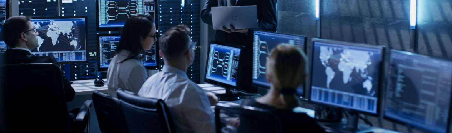 A group of security officers sitting behind computer screens in a control room environment