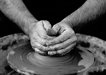 image of mans hands shaping clay on a pottery wheel