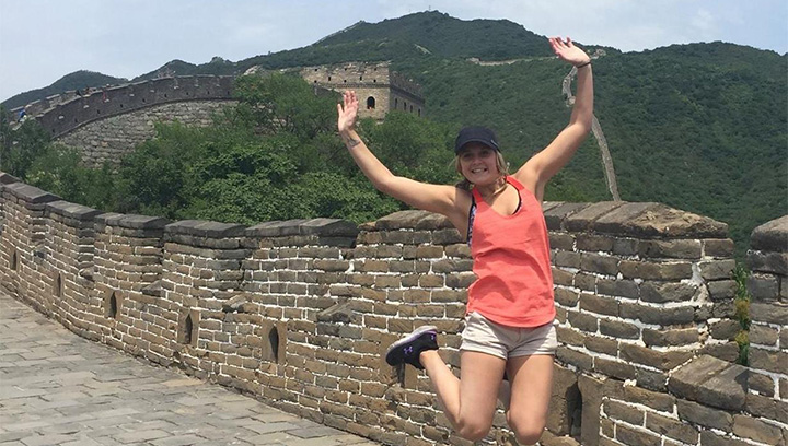 Melissa from Georgian College's Tourism – Marketing and Product Development program jumping with her arms in the air in front of the Great Wall of China