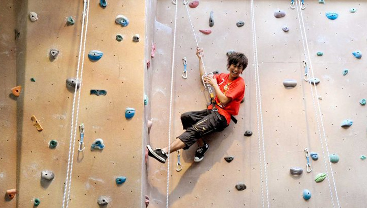 male student in a harness on the rock climbing wall in the Athletics and Fitness Centre at the Barrie Campus