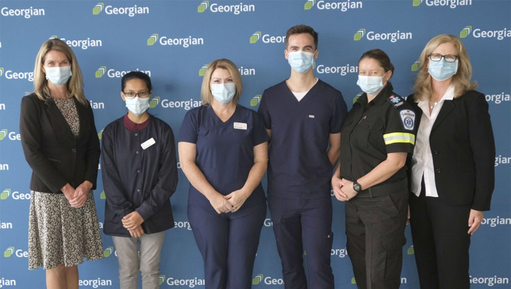 Minister Dunlop and MaryLynn West-Moynes, President and CEO of Georgian, stand with four Georgian Health, Wellness and Sciences students
