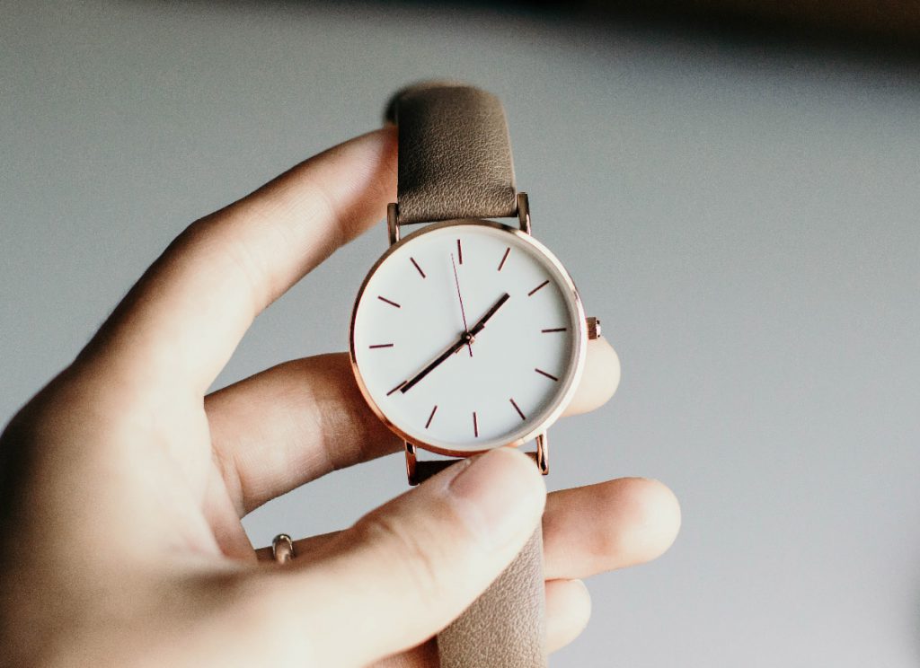 a hand holding a watch made with rose gold and a copper wrist band
